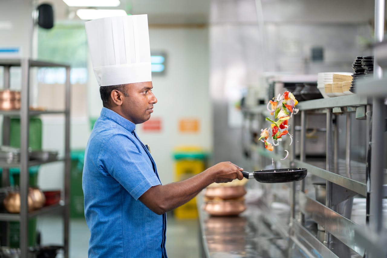 Chef skillfully flipping colorful vegetables in a bustling commercial kitchen.